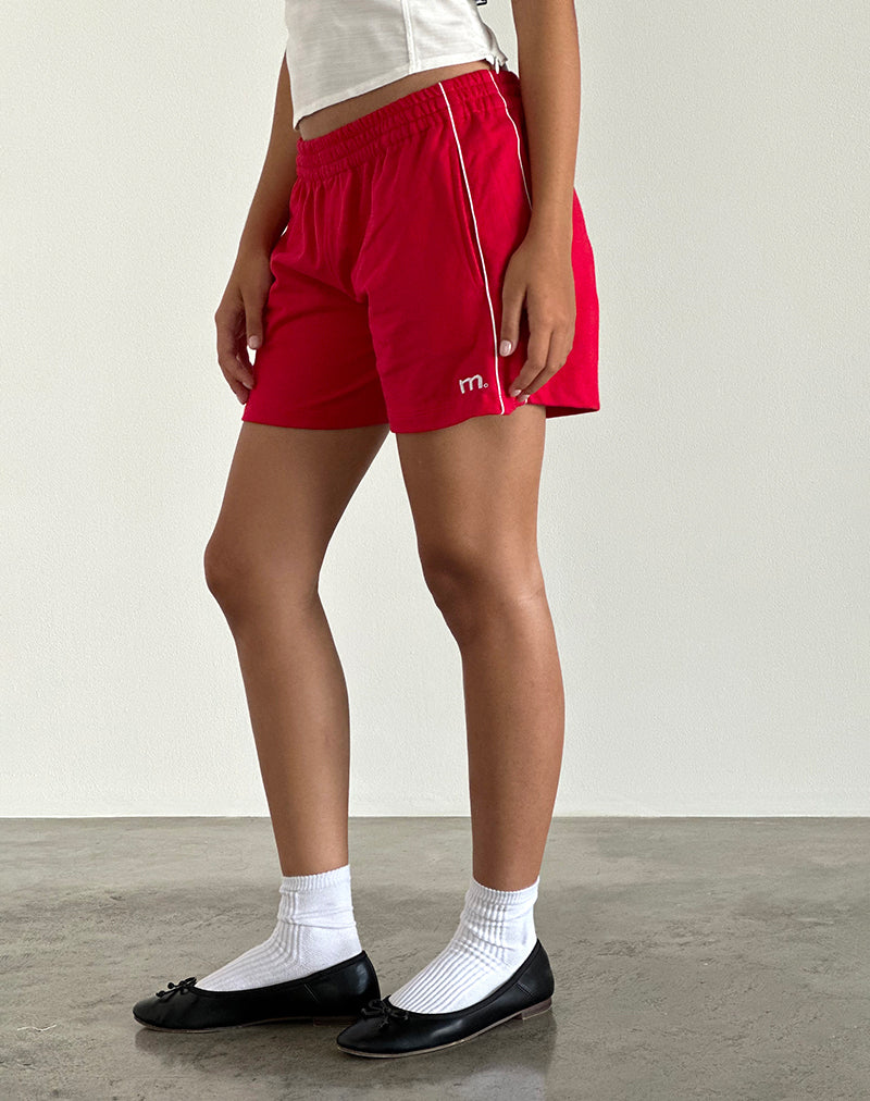 imagen del pantalón corto Thera en rojo tango con ribetes en blanco roto y emblema de la M