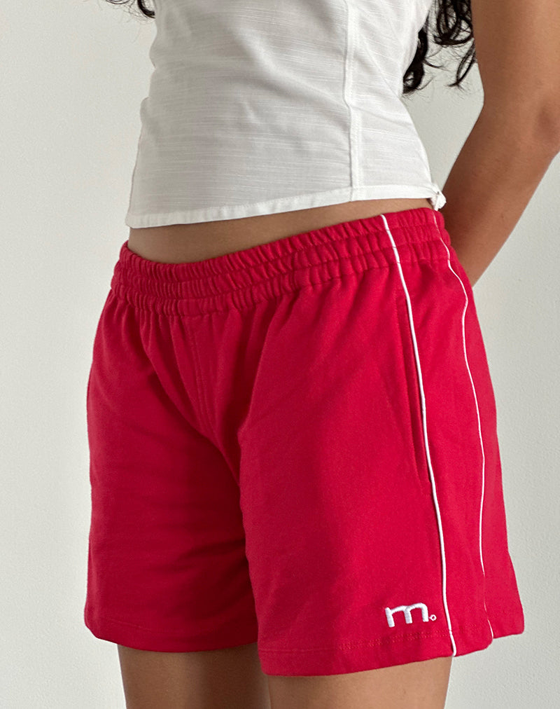 imagen del pantalón corto Thera en rojo tango con ribetes en blanco roto y emblema de la M
