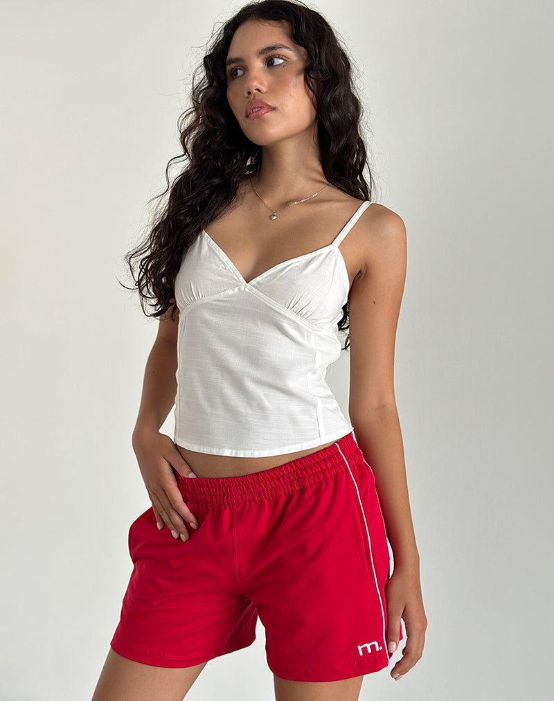 imagen del pantalón corto Thera en rojo tango con ribetes en blanco roto y emblema de la M