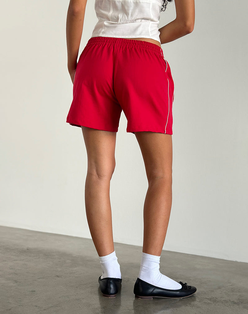 imagen del pantalón corto Thera en rojo tango con ribetes en blanco roto y emblema de la M